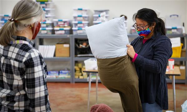 Girl puts case on pillow while teacher watches